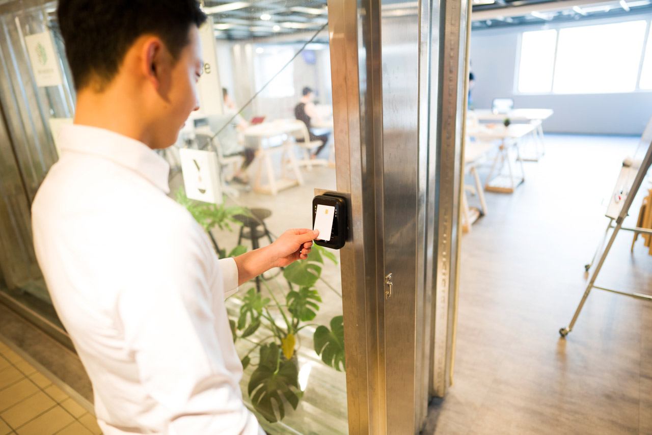 Young taiwanese man unlocking door at his office with an electronic key card